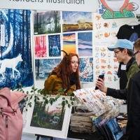A visitor shows something on their smartphone to an exhibitor at a booth in the New Artist Alley at the Manga Comic Con 2024.
