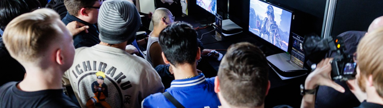 mehrere Personen sehen einem Spieler beim Computerspiel zu im Gamesroom der Manga-Comic-Con 2024