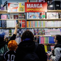 Visitors at an exhibition booth with manga magazines at the Manga Comic Con 2024.
