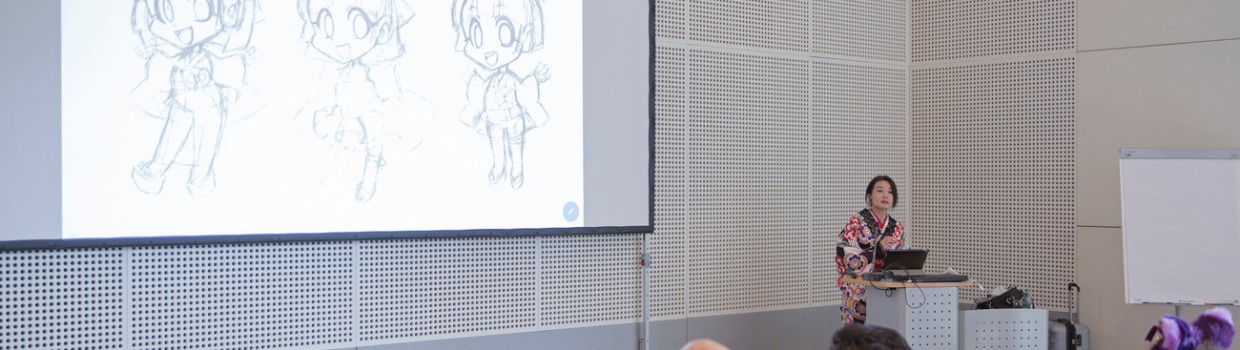 Mangaka Emiko Takano hält einen Vortrag vor Publikum während der Manga-Comic-Con 2024 und zeigt eine Präsentation auf einer großen Leinwand zu ihren Zeichentechniken