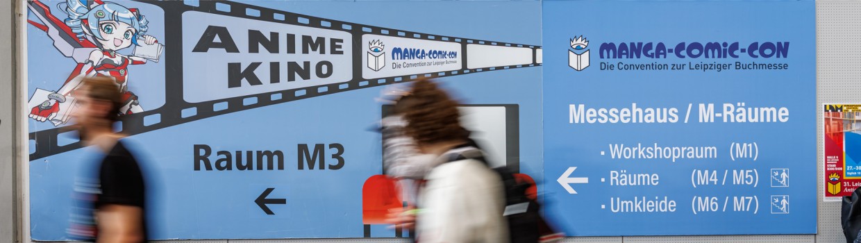 blaues Wegweiserschild zum Anime Kino auf der Manga-Comic-Con 2025 mit vorbeilaufenden Personen
