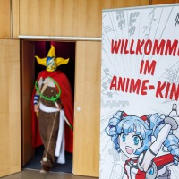 Roll-up-Plakat mit der Aufschrift "Willkommen im Anime-Kino" auf der Manga-Comic-Con 2025 neben der Eingangstür zum Kinoraum