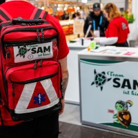 eine Personen vom Awareness Team SAM der Manga Comic Con 2025 läuft am Stand vorbei, dabei sieht man deutlich den roten Rucksack des Teams