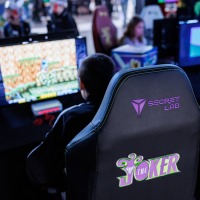 mehrere Personen spielen an Computern im Gamesroom der Manga-Comic-Con 2025, im Vordergrund ist ein Gamingchair von Secret Lab zu sehen
