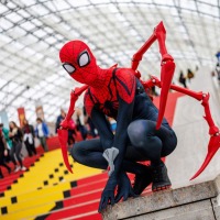 Person im Spider-Man-Kostüm posiert vor der roten Treppe im Eingangsbereich der Glashalle der Leipziger Messe auf der Manga Comic Con 2025