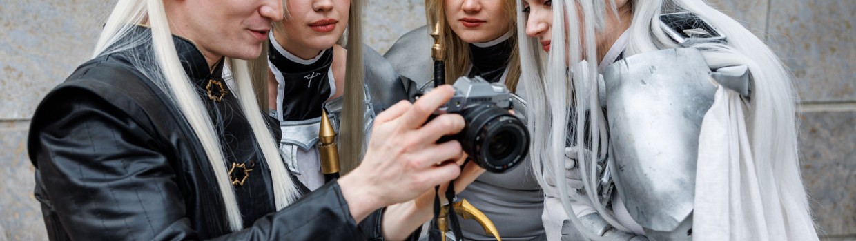 Four cosplayers wearing long white wigs and look together at a camera at Manga Comic Con 2025.