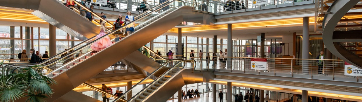 Das Atrium des Congress Center Leipzig mit vielen Besucher:innen auf Rolltreppen und Gängen