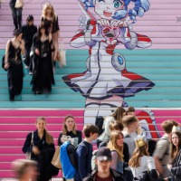 Visitors of the Manga Comic Con 2025 in front of and on a staircase featuring the Leipzig Trade Fair mascot.
