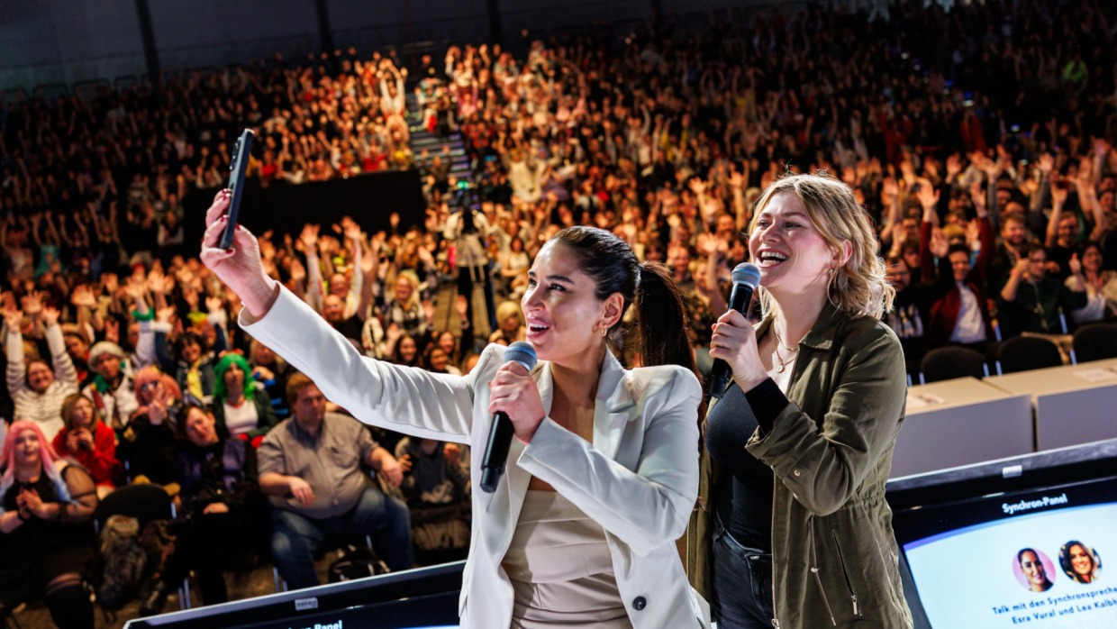 Esra Vural takes a selfie on the Main Stage of the Manga-Comic-Con 2025 in front of a full audience
