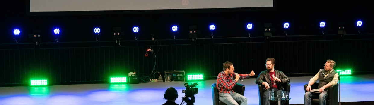 Three people in conversation on a stage at the Leipzig Book Fair
