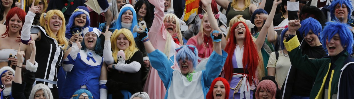 Großes Gruppenfoto von Cosplayern, die alle fröhlich lachen und teilweise die Arme hochreißen.